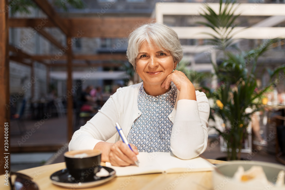 old age, leisure, retirement and people concept - happy senior woman with coffee and notebook at street cafe old age, leisure, retirement and people concept - happy senior woman with coffee and notebook at street cafe
