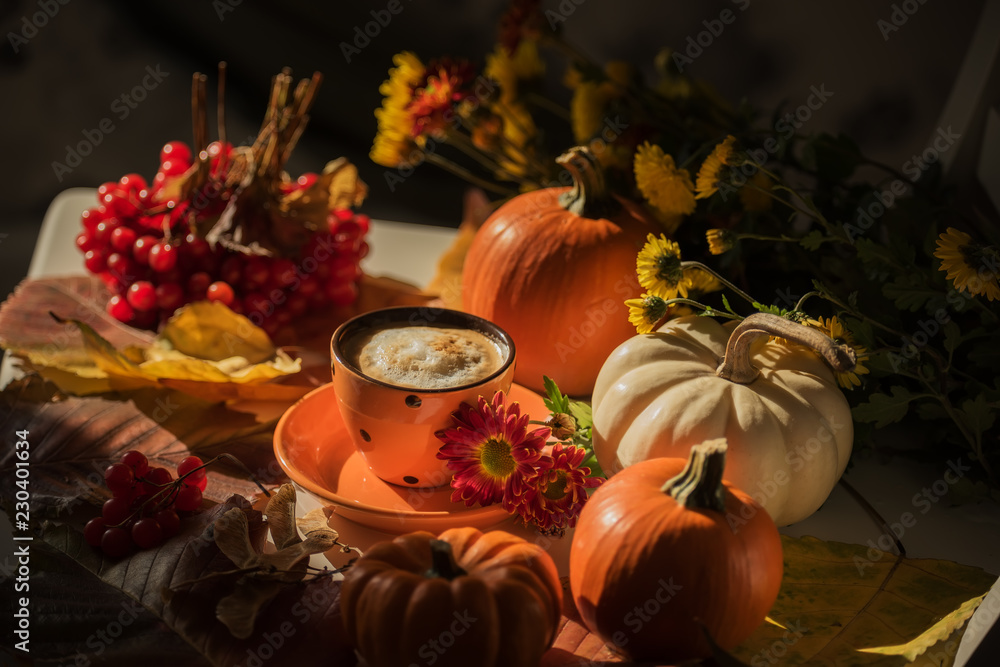 Aromatic coffee in a red cup and autumn lsitja, mini pumpkins and berries. Dark photo.Autumn still life.

