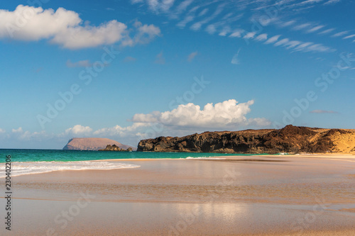 Idyllic landscape of a white sand beach with turquoise water on a hot summer day. Amazing scenery of Playa de la Conchas on La Graciosa Island, in the Canary Islands, Spain.