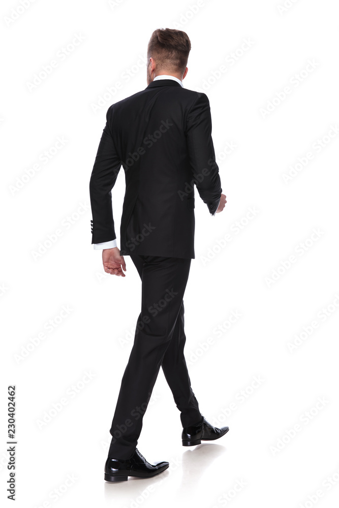back view of a young man in tuxedo walking