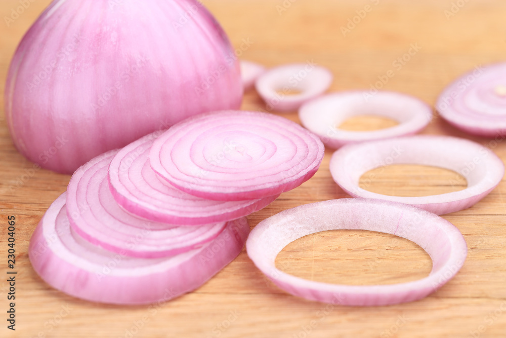 Red onion or Allium cepa half cut and sliced on a wooden cutting board Red onion or Allium cepa half cut and sliced on a wooden cutting board