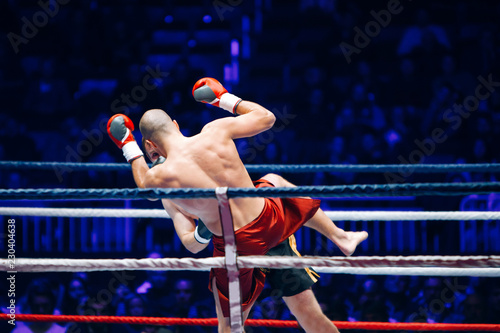 Cuadro en lienzo The boxer in the ring strikes the opponent in the arena of full light