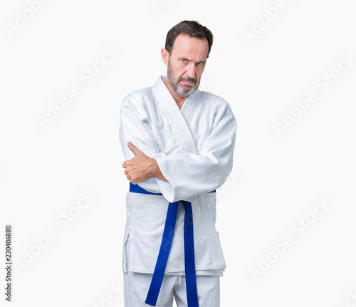 Handsome middle age senior man wearing kimono uniform over isolated background skeptic and nervous, disapproving expression on face with crossed arms. Negative person.