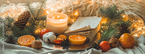 Book and Tangerines in a winter composition, Christmas trees, candles, cones, cotton, cinnamon. Symbol of New Year and Christmas