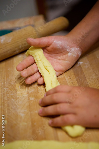 Children's hands knead the dough for the cake.