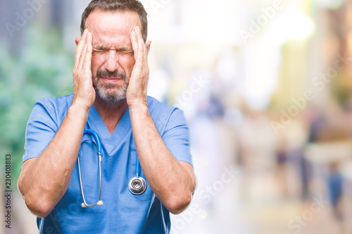 Middle age hoary senior doctor man wearing medical uniform over isolated background with hand on head for pain in head because stress. Suffering migraine.