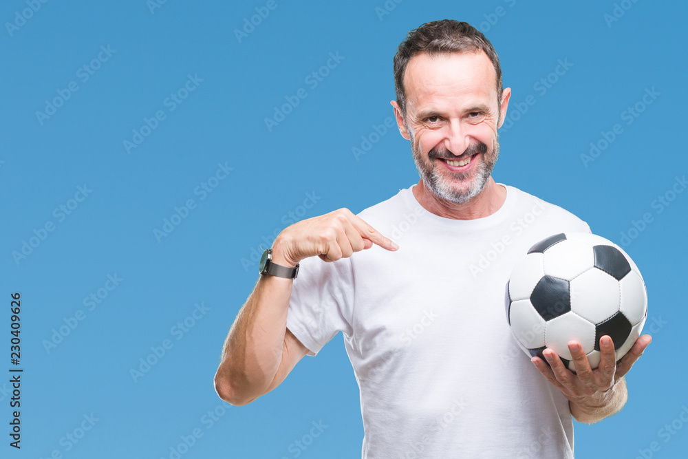 Middle age hoary senior man holding soccer football ball over isolated background with surprise face pointing finger to himself Middle age hoary senior man holding soccer football ball over isolated background with surprise face pointing finger to himself
