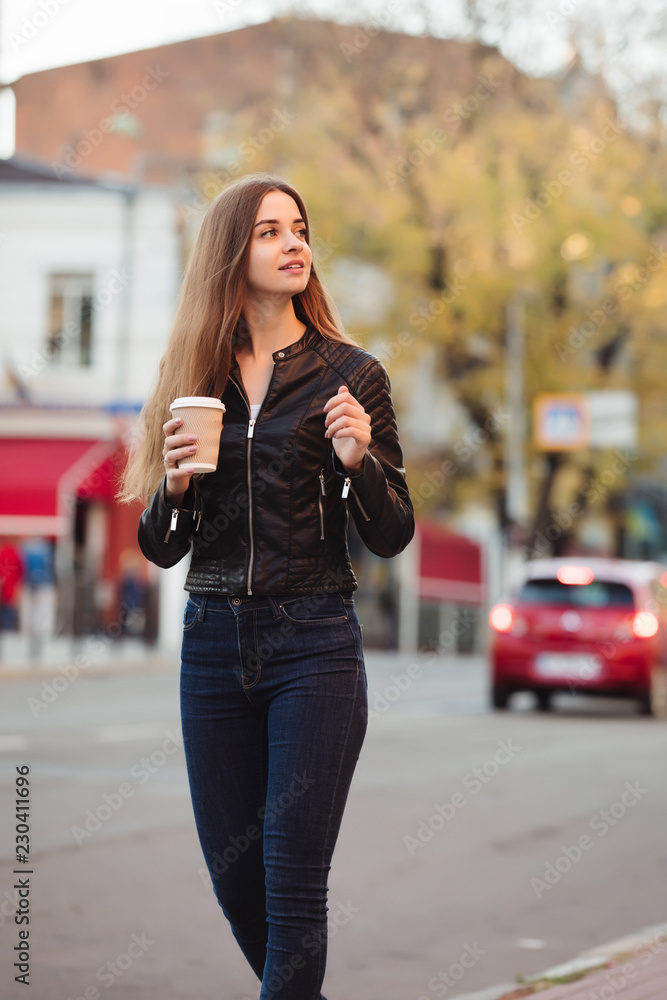 Beautiful woman holding paper coffee cup and enjoying a walk in the city