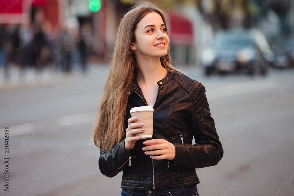 Fototapeta premium Beautiful woman holding paper coffee cup and enjoying a walk in the city