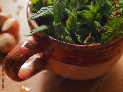 A cup of mint leaves and hazelnuts on wooden background photo