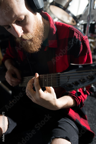 High angle portrait of handsome bearded man playing guitar in studio during rehearsal, copy space