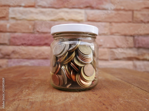 jar coins on brick wall background