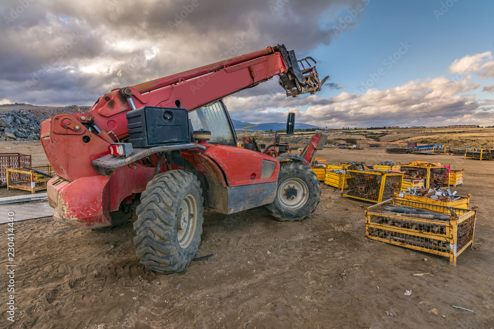 Fototapeta premium Forklift on a construction site, preparing to raise construction parts