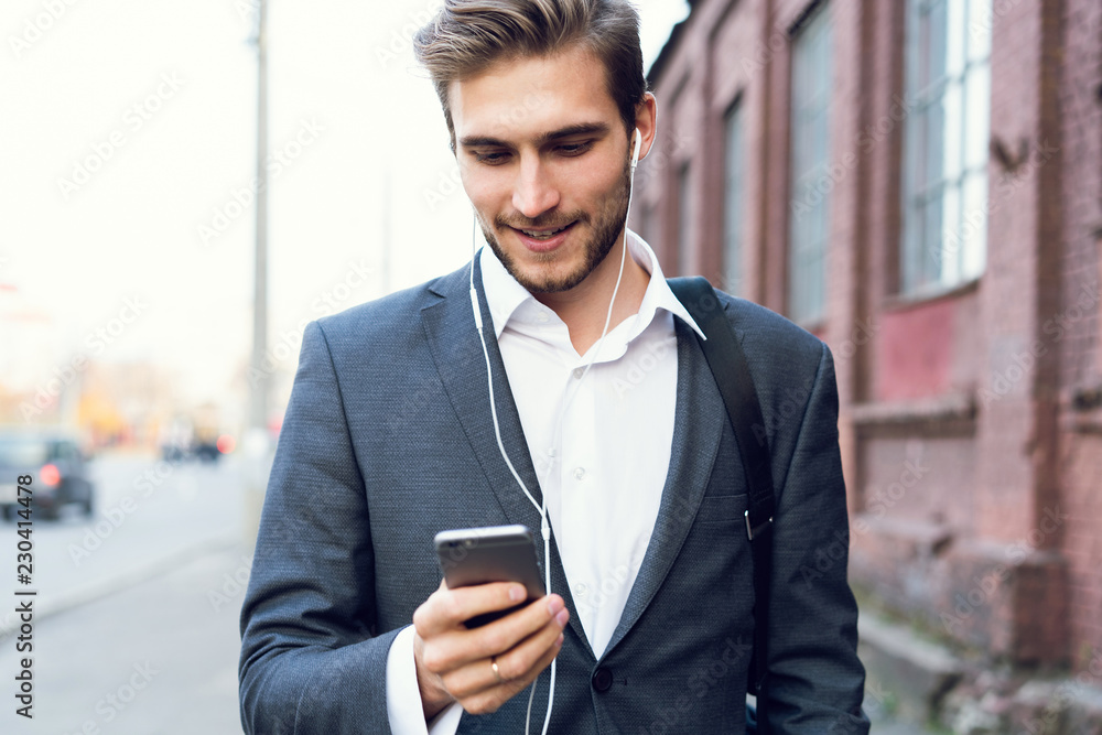 Happy attractive young businessman walking and using mobile phone outdoors. Happy attractive young businessman walking and using mobile phone outdoors.