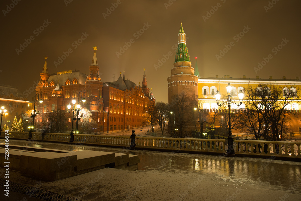 Moscow, Russia. On Background Ancient Famous Architectural Buildings Of State Historical Museum And Moscow Kremlin Corner Arsenal Tower On Manege Square With Illumination Lamps In Evening At Winter.