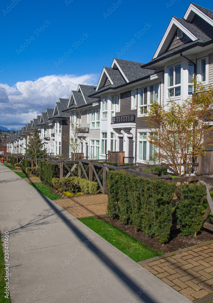 Suburban residential street townhomes. On bright sunny spring day against bright blue sky. Suburban residential street townhomes. On bright sunny spring day against bright blue sky.