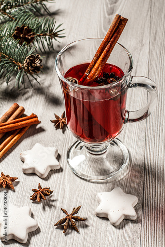 Glass of Christmas mulled wine with spices and cookies on wooden boards