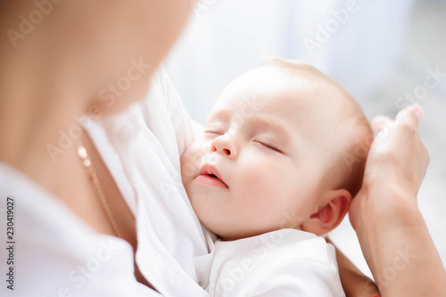 Baby sleeping on the mother's chest. Young mother cuddling baby