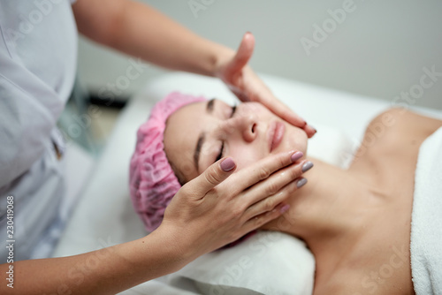 Hands of cosmetology specialist applying facial mask making skin hydrated and face glowing and skin