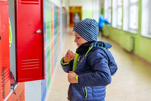 Bild auf Leinwand Child boy dressing his autumn jacket in school