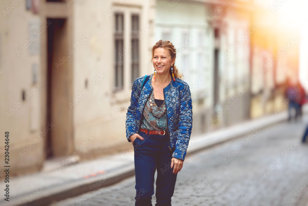 Happy young woman  walking along on city street.
