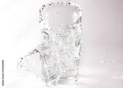 Falling and crashing glass of water. Shards of glass and splashing water