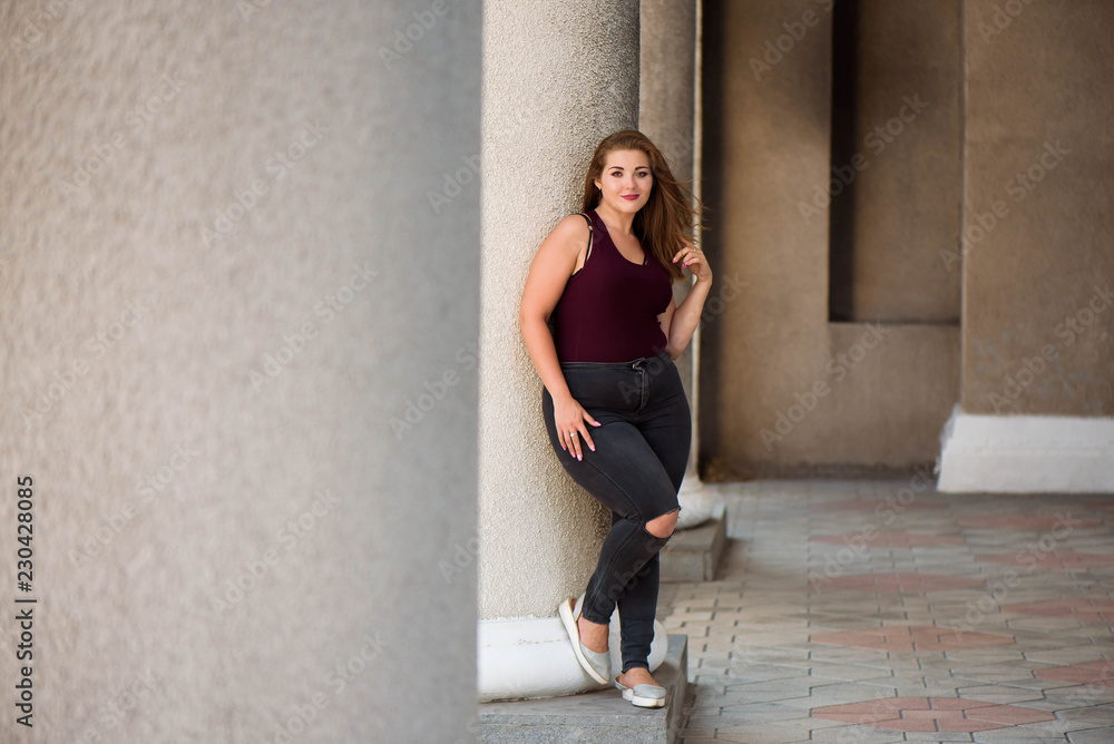 Young stylish woman walking on the city street in summer. Plus size model.