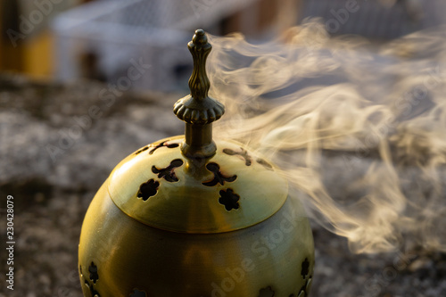 incense burner censer with smoke and blurred background.