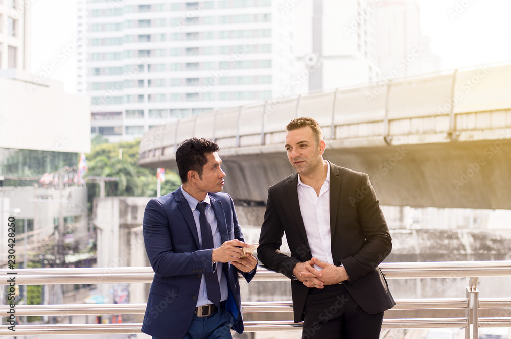 Image of businessman talking and consult while standing together outdoor Image of businessman talking and consult while standing together outdoor