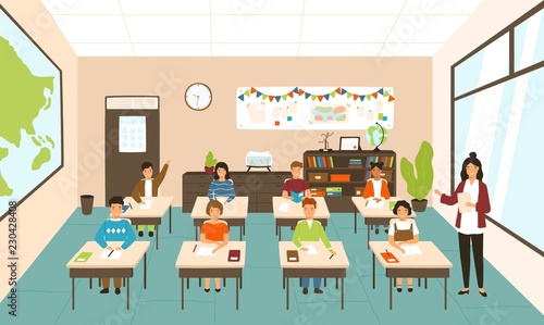 Pupils sitting at desks in modern classroom, young female teacher teaching them. Elementary school boys and girls studying on lesson in class. Colorful vector illustration in flat cartoon style.