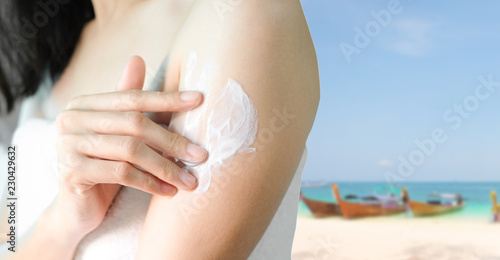 Woman applying arm cream,lotion with blur sea background, sun lotion concept, Hygiene skin body care concept.