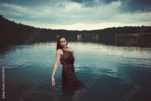 Beautiful young girl by the lake. Girl in a dress on the beach