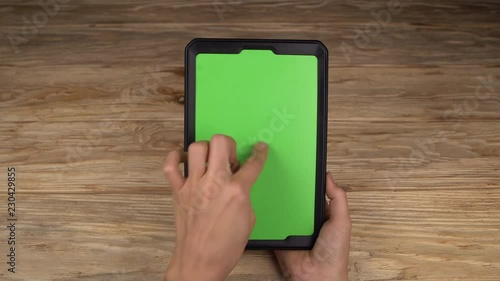 A woman holds a tablet PC with a green screen for your own custom content.