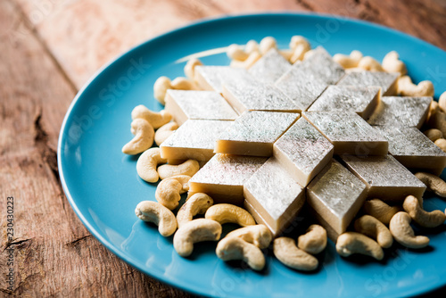 Kaju Katli is a Diamond shape Indian sweet made using cashew sugar and mava, served in a plate or bowl over moody background. selective focus