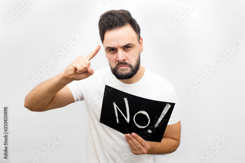Serious and angry man stand and hold plate with written word no. He points up and look scarely on camera. Allso man looks like threat. Isolated on white background. photo