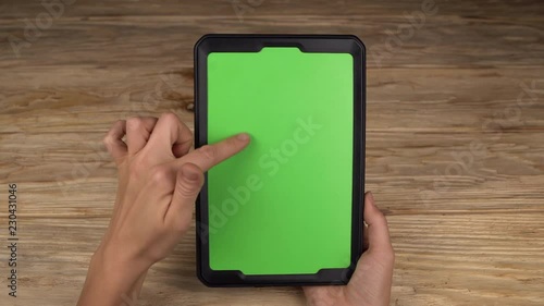 A woman holds a tablet PC with a green screen for your own custom content.