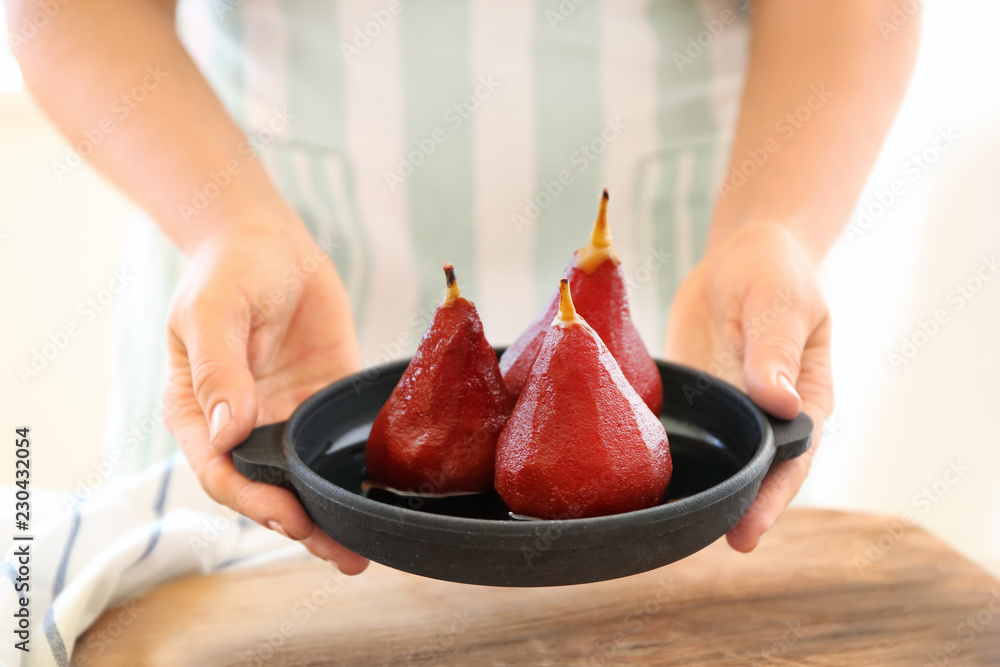 Woman holding pan with sweet pears stewed in wine, closeup