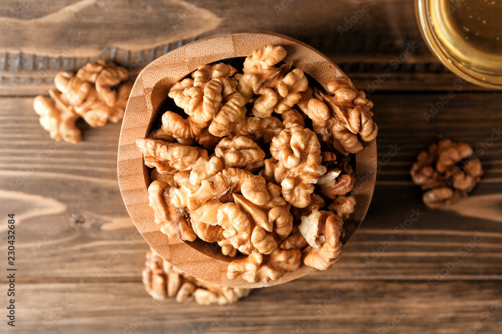 Fototapeta premium Bowl with tasty walnuts on wooden table