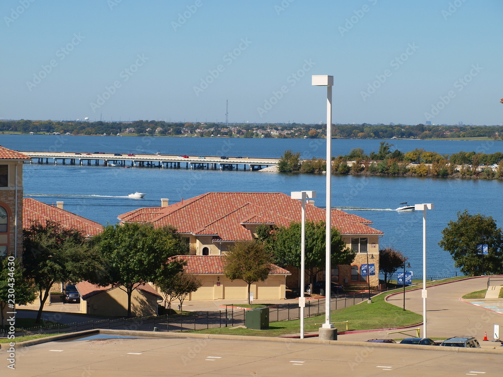 Fototapeta premium The Interstate 30 Causeway Bridge over Lake Ray Hubbard Recreational Area. The red tile roofs are counterpoint to the blue sky and water.
