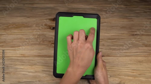 A woman holds a tablet PC with a green screen for your own custom content.