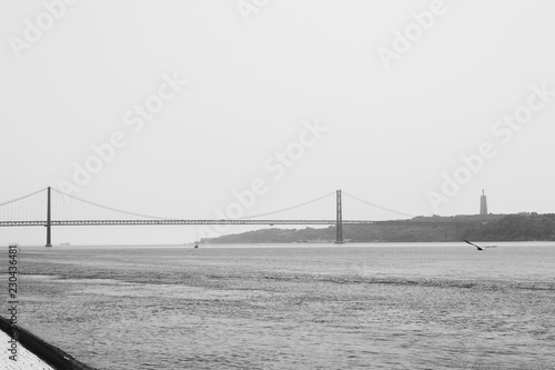 Black and white view of 25 April Bridge and Christ the King monument in Lisbon, Portugal