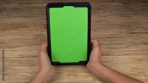 A woman holds a tablet PC with a green screen for your own custom content.