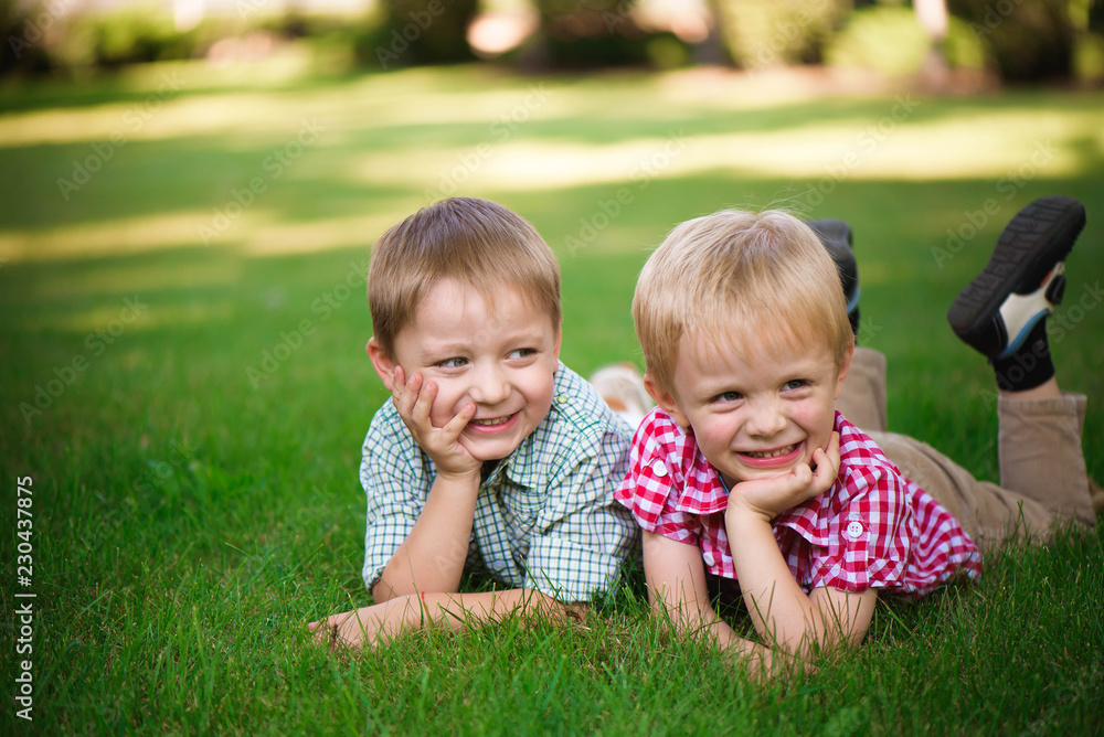 Two brothers lying on the grass in a park outdoors, smiling and Two brothers lying on the grass in a park outdoors, smiling and