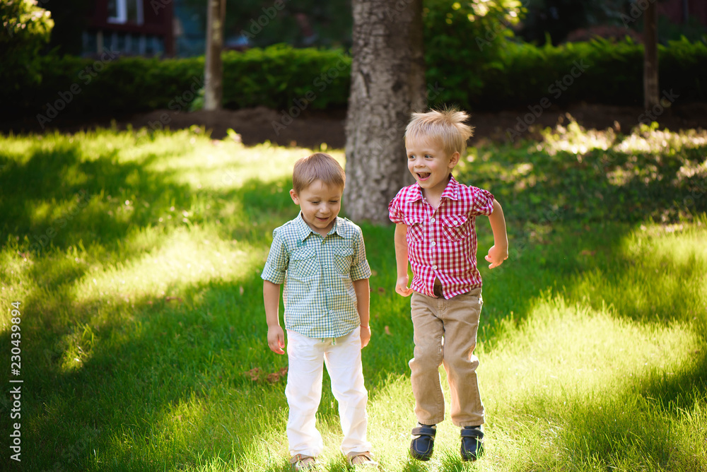 Fototapeta premium Two boys brothers playing and jumping outdoors in a park.
