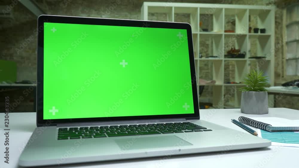 Desolate working space, working computer with green screen switched on, white desk and notebook, indoor Desolate working space, working computer with green screen switched on, white desk and notebook, indoor