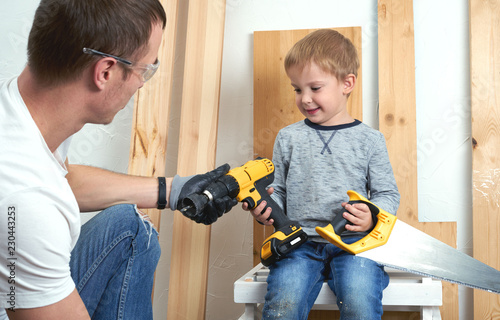 Family time: Dad shows his son hand tools, a yellow screwdriver and a hacksaw. They need to drill and drill boards for repair.