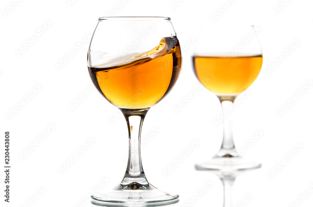 A round glass with brandy and a splash of drink inside A round glass with brandy and a splash of drink inside