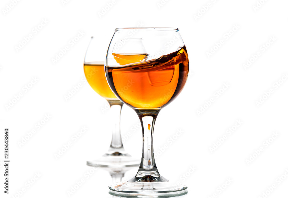 A round glass with brandy and a splash of drink inside A round glass with brandy and a splash of drink inside