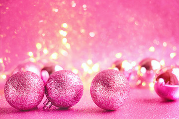Pink shiny christmas balls on glittering abstract pink background. christmas and new year holidays concept. symbol of festive winter season. template for design