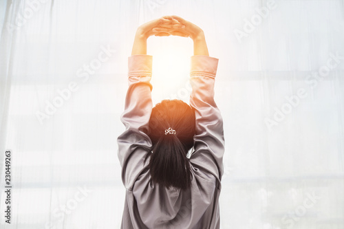 Back of view Woman stretching her arm after wake up on bed and looking outside windows in bedroom feeling so fresh and relax in the morning,Healthcare Concept